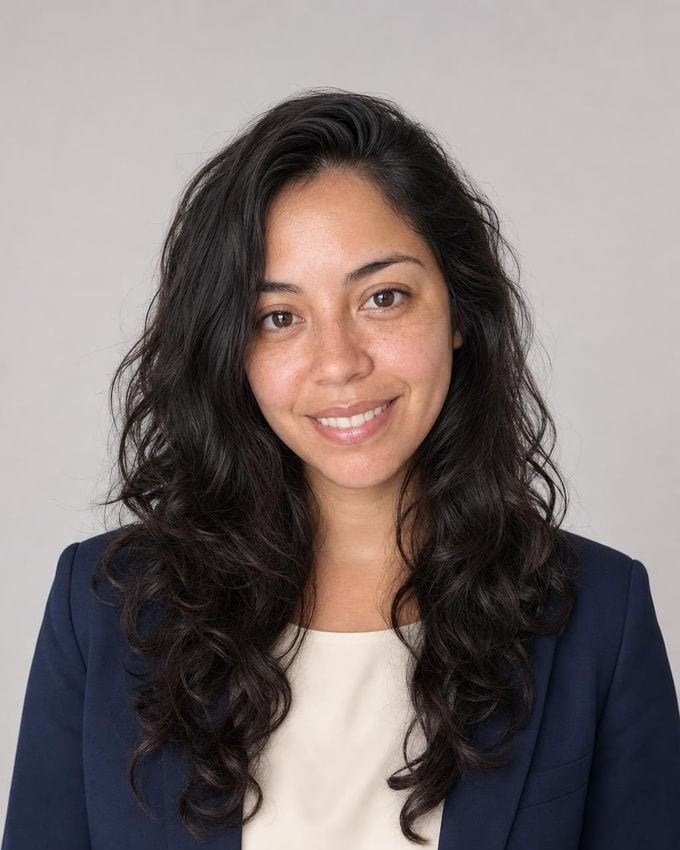 The Standard: a woman in a navy blazer and ivory shell against a light grey seamless backdrop, evenly lit.